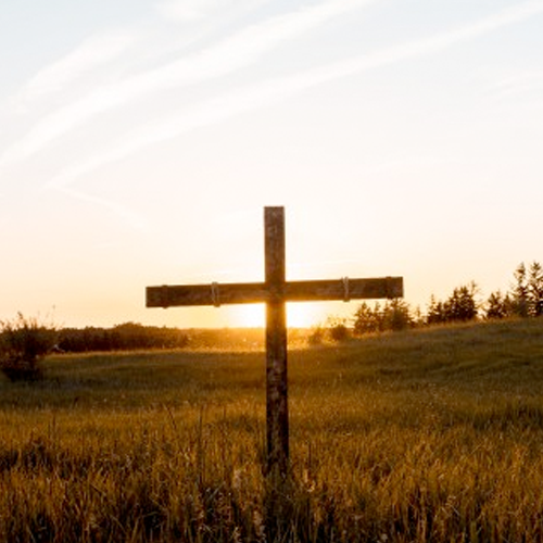 A weathered cross sits in a grassy field